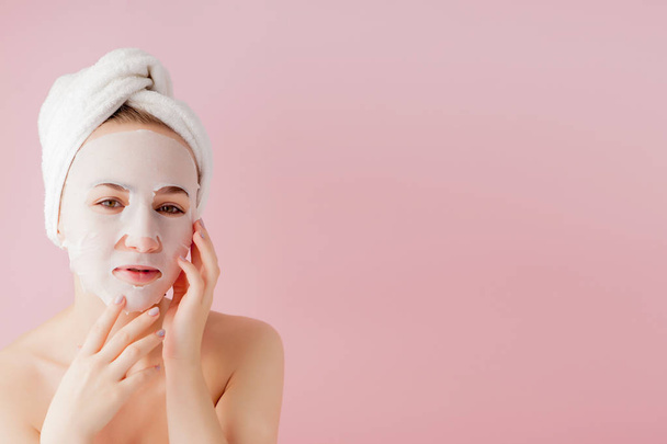 Beautiful young woman is applying a cosmetic tissue mask on a fa - Фото, зображення