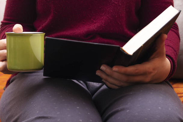 Nahaufnahme weiblicher Hände, die Kaffee halten und ein Buch lesen - Foto, Bild
