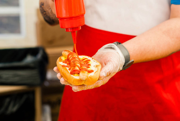 chef hands adding ketchup to hot dog - Photo, Image