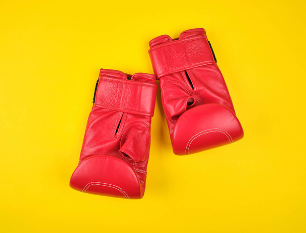 pair of red leather boxing gloves on a yellow  background - 写真・画像