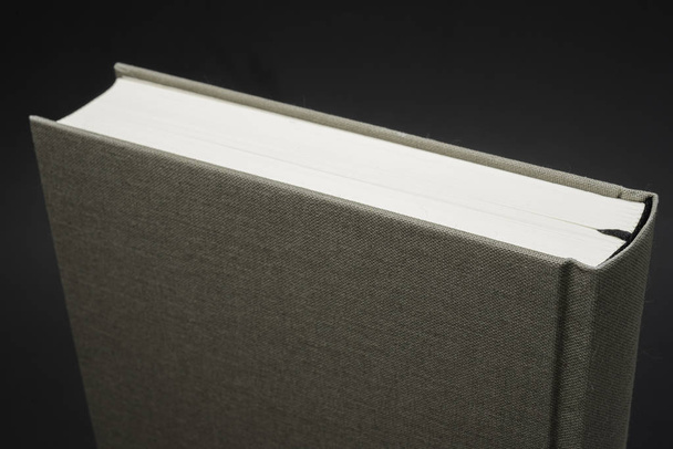 Uma visão de perto da parte superior de um livro encadernado a pano com marcador de seda preta permanente em um fundo escuro
. - Foto, Imagem