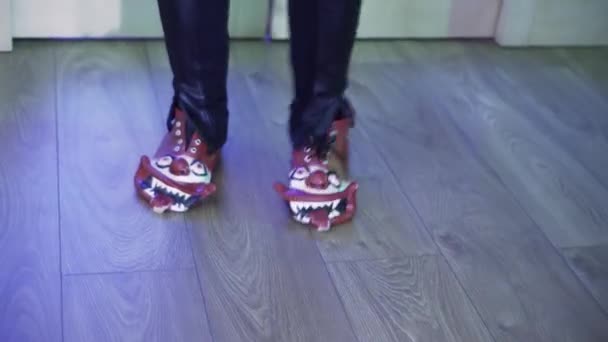 Someone wearing clown-shaped shoes and dark pants joyfully dances in room. - Footage, Video