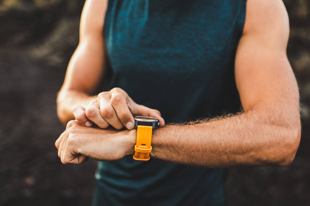 Young athletic man using fitness tracker or smart watch before r - Foto, Imagem