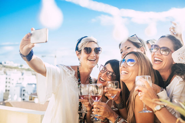 Donne felici amiche in festa all'aperto - gruppo di giovani donne si divertono insieme in amicizia festeggiando con felicità e ride e scattando una foto di selfie con lo smartphone - Foto, immagini