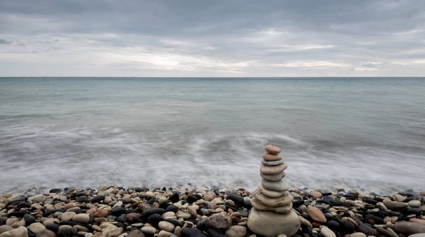 Pyramid of balancing stones , in the wavy ocean - Photo, Image