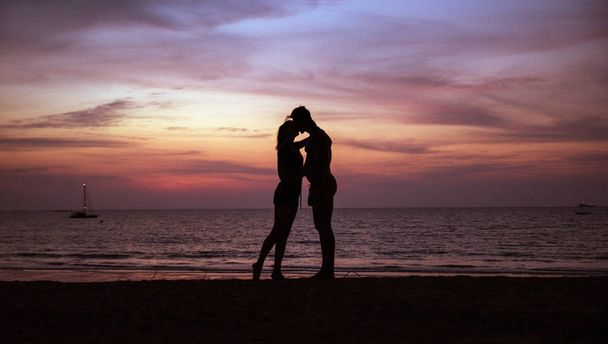 Jeune couple embrassant sur une plage tropicale, coucher de soleil en arrière-plan
 - Photo, image