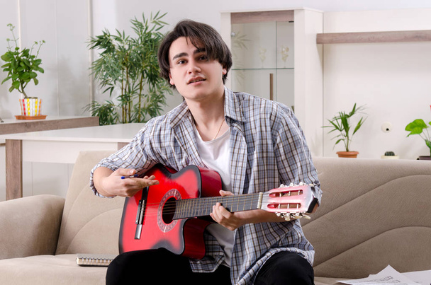 Młody człowiek z gitarą w domu - Zdjęcie, obraz