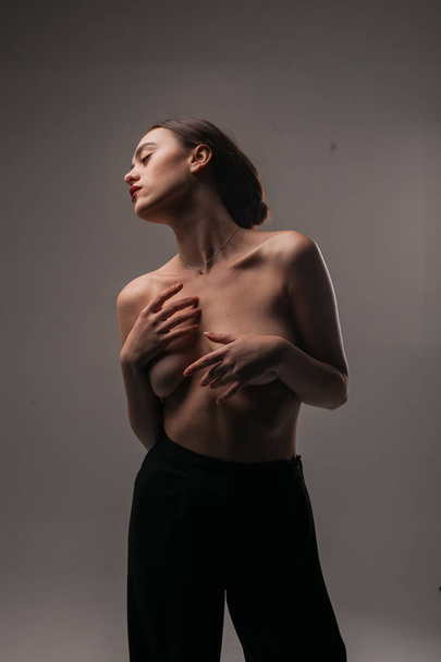 Beautiful girl in the studio covering her breasts with her hands  - 写真・画像