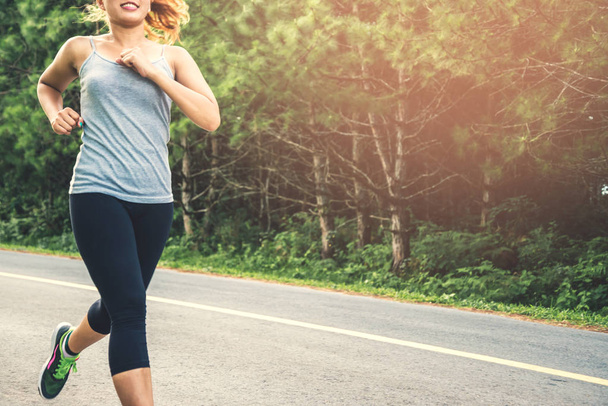 女性は通りを走る運動をする。自然公園運動ランニング健康リラックス. - 写真・画像