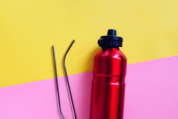 明るいピンクと黄色の背景、持続可能な製品のライフスタイルとゼロ廃棄物の概念上の飲み物のための金属ステンレスストローと再利用可能なボトルのフラットレイ  - 写真・画像