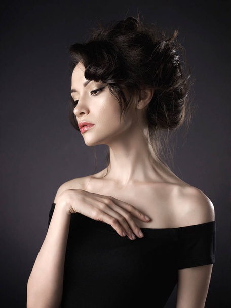 Mooie vrouw met elegante kapsel op zwarte achtergrond - Foto, afbeelding