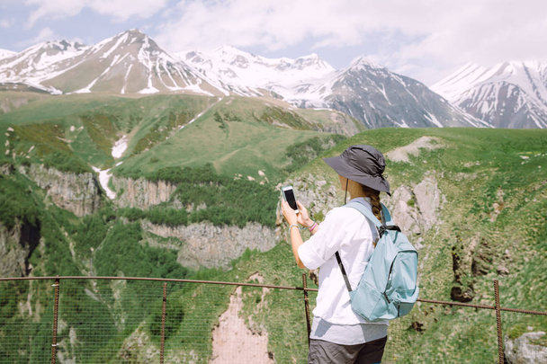 Dağların cep telefonuyla fotoğraf çeken genç kadın turist - Fotoğraf, Görsel