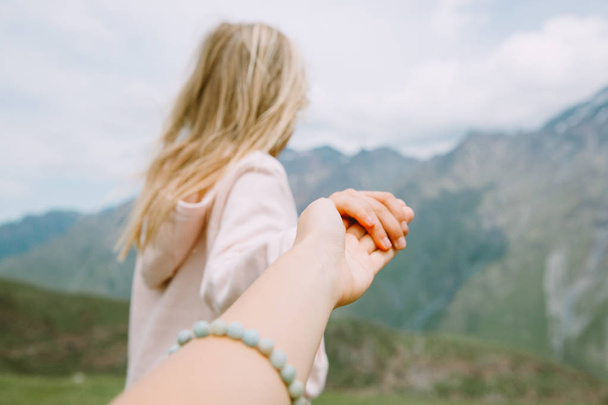 Klein meisje dat de hand vasthoudt en de persoon naar de bergen trekt - Foto, afbeelding
