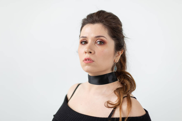 Portrait d'une belle jeune femme romantique avec un ruban noir sur le cou posant sur un fond blanc. Concept de beauté
 - Photo, image
