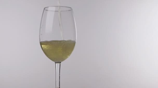Pouring white wine from bottle into glass on a white background, close up. - Video, Çekim
