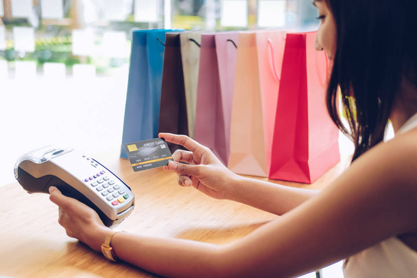 woman using credit card swiping machine with shopping bags on ta - Valokuva, kuva