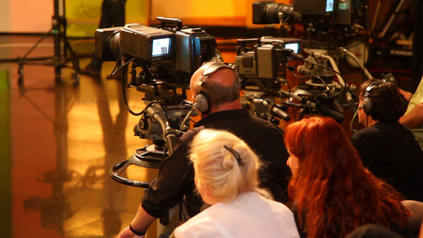 Widok cameramans i widzów w dużym studiu telewizyjnym z tyłu podczas filmowania - Materiał filmowy, wideo