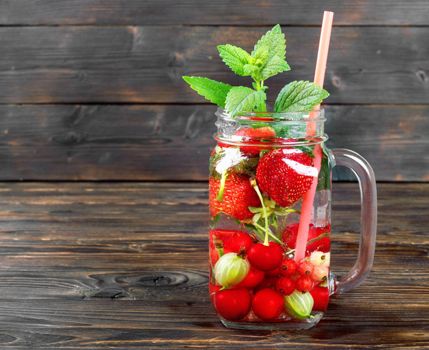 Fresh cool drink of ripe juicy cherry, strawberry, currant and gooseberry berries - Foto, Bild