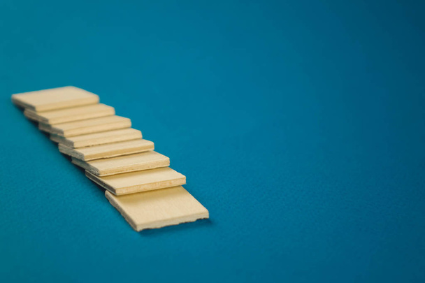 standing on top of each other small wooden blocks on a blue background - Photo, Image