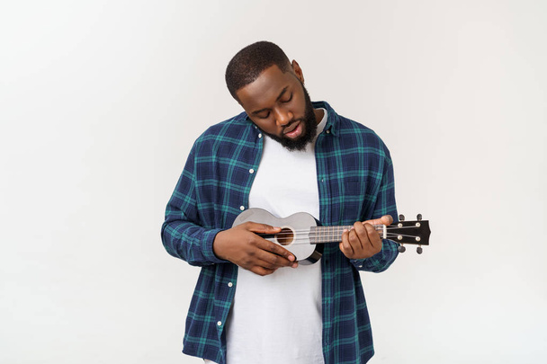 Giovane bello africano americano uomo gioca ukulele isolare su sfondo bianco
, - Foto, immagini