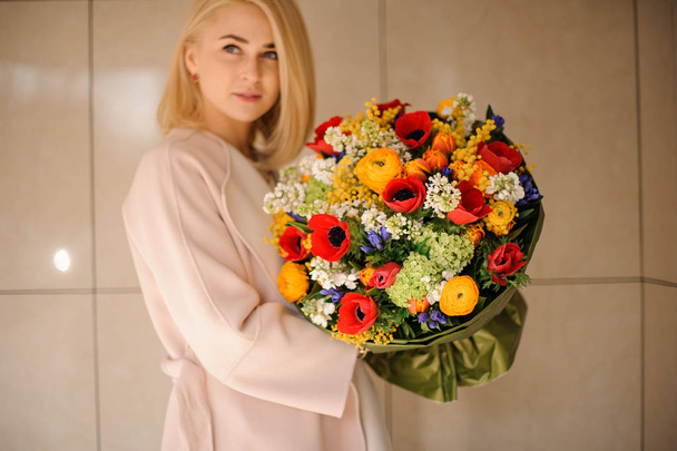 Woman holding a spring bouquet of multicolored flowers - 写真・画像