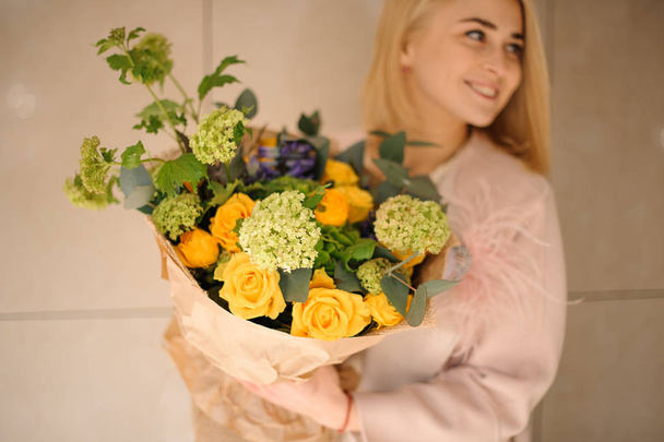 Smiling woman holding a bouquet of tender bright yellow roses - Foto, imagen