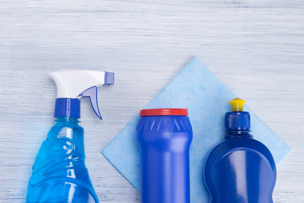 on a light background, blue cloth and blue bottles with powder and surface cleaning fluids - Photo, image