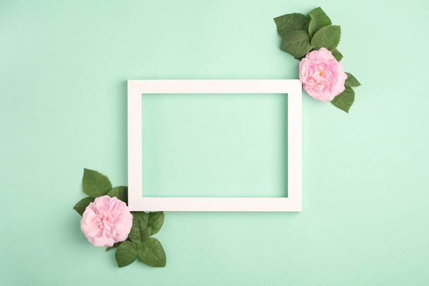 Beautiful rose flowers and blank frame on pastel mint background. Soft light color. Top view, copy space. - 写真・画像