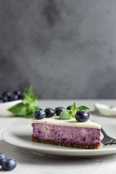 Piece of blueberry cheesecake, fresh blueberries and mint on a light stone background. Copy space. - Valokuva, kuva