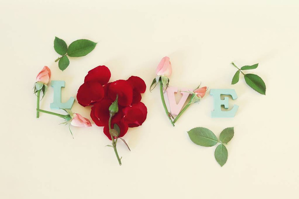 Aşk kelimesi gül tomurcukları, yaprakları ve kalpleri, romantik bir tebrik ile çok renkli harflerle dekore edilmiştir - Fotoğraf, Görsel