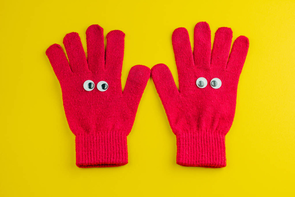 top view flat lay   two gloves with eyes on a yellow background - Foto, immagini