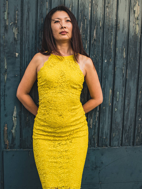  Modelo asiático de 40 años en un vestido de encaje amarillo de pie dreamil
 - Foto, Imagen
