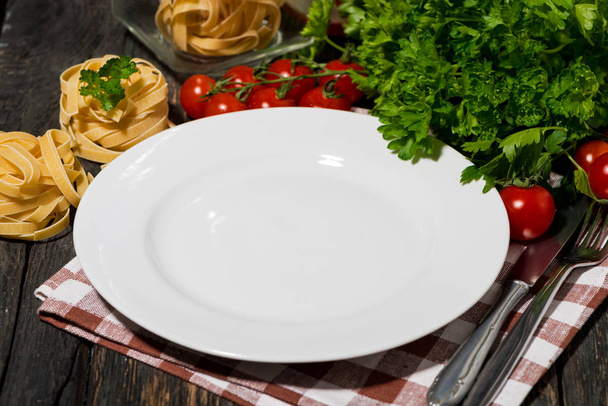 table setting with white plate, pasta and vegetables  - Fotó, kép