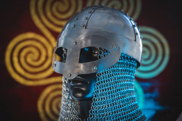 Soldier Viking helmet with chain mail of iron on red shield of wood and golden triskel - 写真・画像