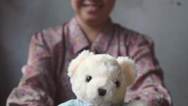 asiatische Dame mit Lächeln schenkt Ihnen einen Teddy mit blauem Tuch. für Liebe eins. Valentinstag. - Filmmaterial, Video