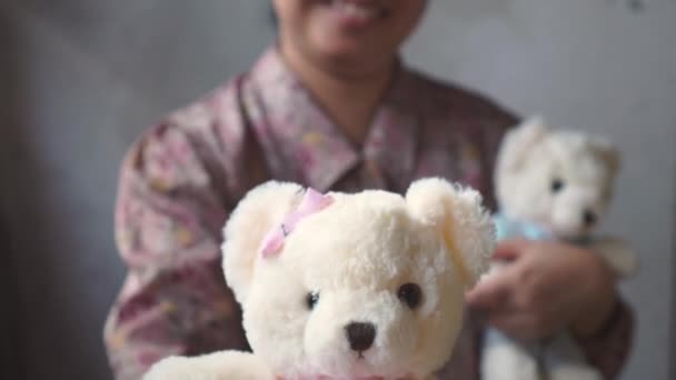 Asian Lady z uśmiechem daje Teddy z różową szmatką do Ciebie. w ramieniu. dla miłości jeden. Walentynki. - Materiał filmowy, wideo