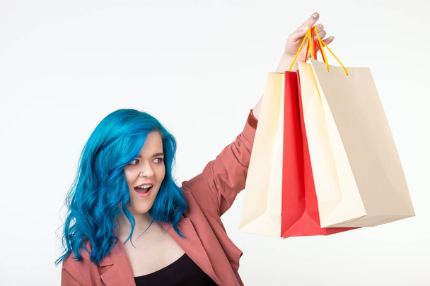 Sale, shopaholic and consumer concept - beautiful girl with blue hair standing with shopping bags on white background - Φωτογραφία, εικόνα