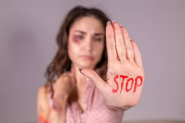 Violência doméstica, protesto e conceito de pessoas mulher morena expressando negação com PARAR em sua mão no quarto cinza
 - Foto, Imagem