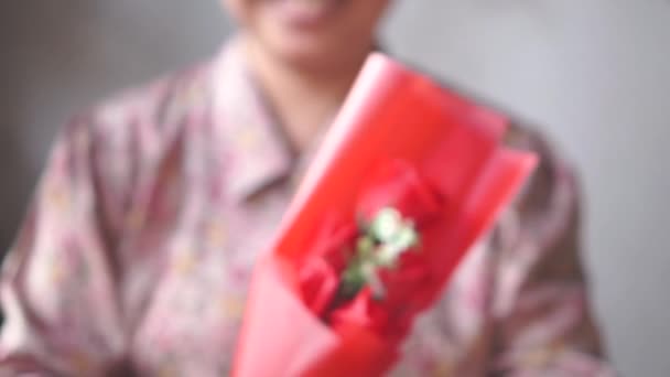 Aziatische Dame met glimlach geeft een boeket van een rode roos aan u. Slow Motion - Video