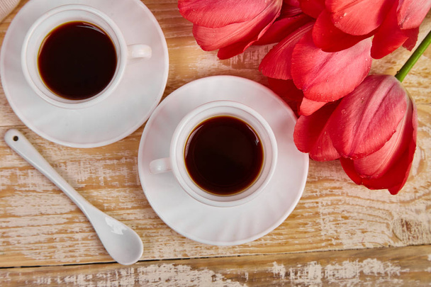 Dwa filiżanki kawy kubek z różowe kwiaty tulipan bukiet na rustykalny drewniany stół z góry, dzień dobry. Kopiuj przestrzeń.  - Zdjęcie, obraz