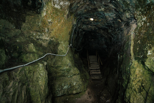 Piękna Jaskinia. Widok z wnętrza ciemnego lochu. Teksturowane ściany jaskini. Obraz tła podziemnego tunelu. Wilgoć wewnątrz jaskini. Oświetlenie wewnątrz jaskini na wycieczki. - Zdjęcie, obraz