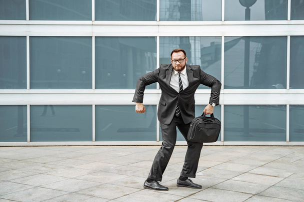Веселий бізнесмен танцює біля будівлі офісу на вулиці
 - Фото, зображення