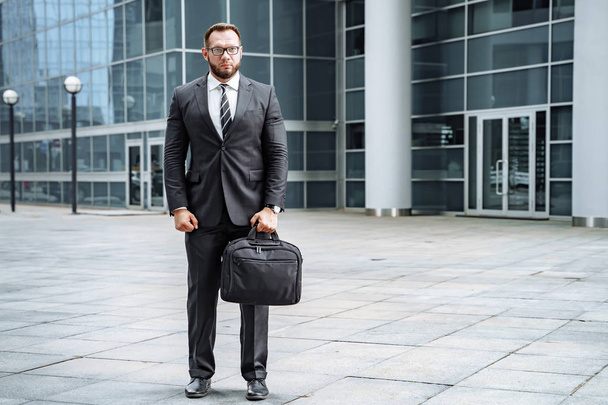 Portrait of a business man in a suit with a bag in his hands on the street - Photo, image