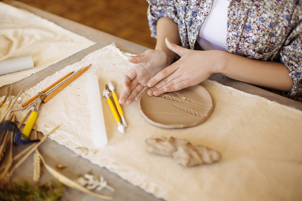 female hands make a plate of clay - Foto, Bild