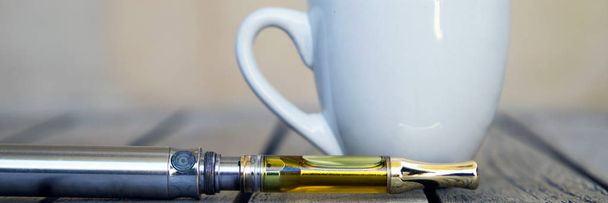 Vape Pen et tasse sur la surface en bois, vapotage d'huile de marijuana, vaporisateur de cannabis
  - Photo, image