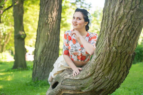 mooie schattige jonge brunette vrouw poseren met haar mooie boom in de groene zomertuin alleen. gelukkig meisje plezier in de natuur, plezier in stadspark en rust. - Foto, afbeelding