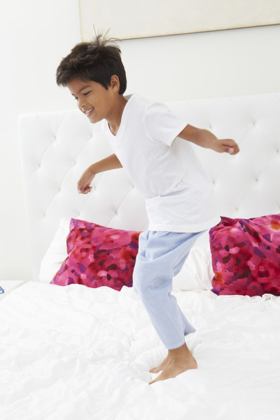 Boy Jumping On Bed Wearing Pajamas - Photo, image