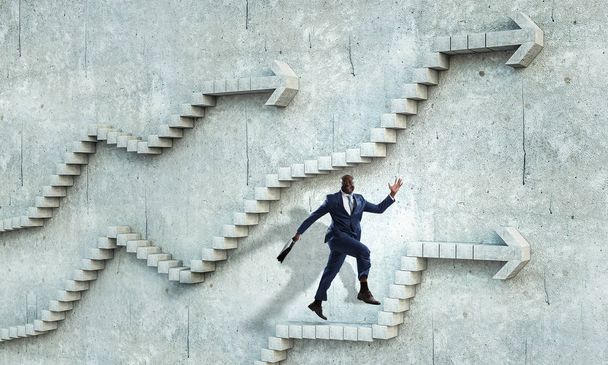 Black businessman climbing stone stairs illustrating career development and success concept. Mixed media - Photo, image