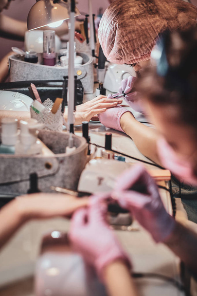 Rušný ateliér manikúry se spoustou pracovních pracovníků a klientů. - Fotografie, Obrázek