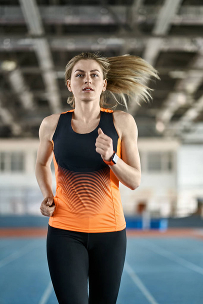 Athletic blonde woman training at indoor stadium - Foto, afbeelding
